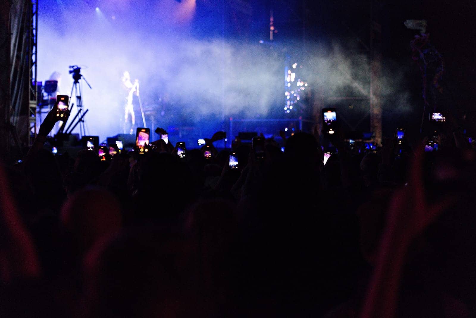 A crowd facing a smoky stage washed in blue light